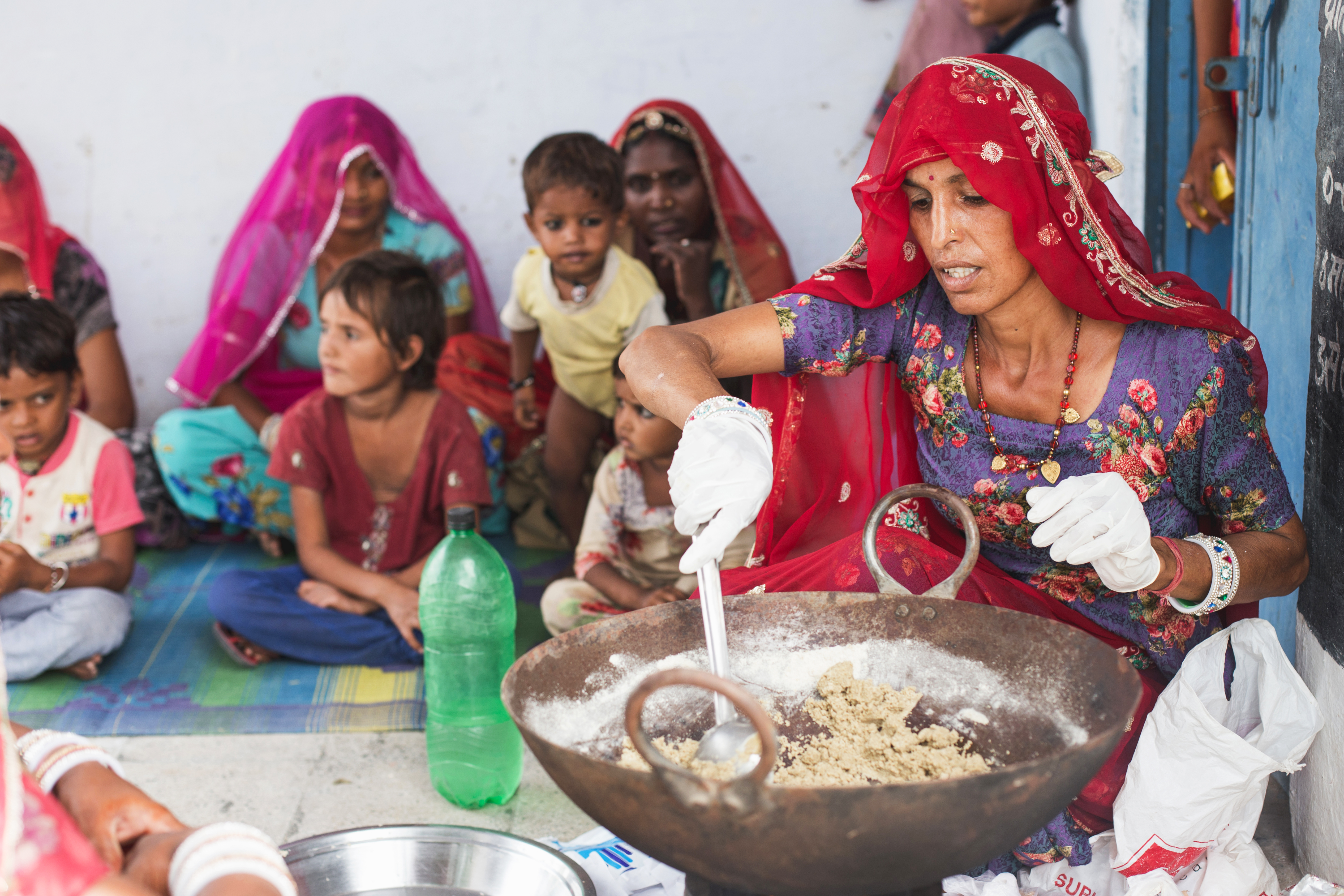 Vrouw uit India bereidt eten met kinderen op de achtergrond