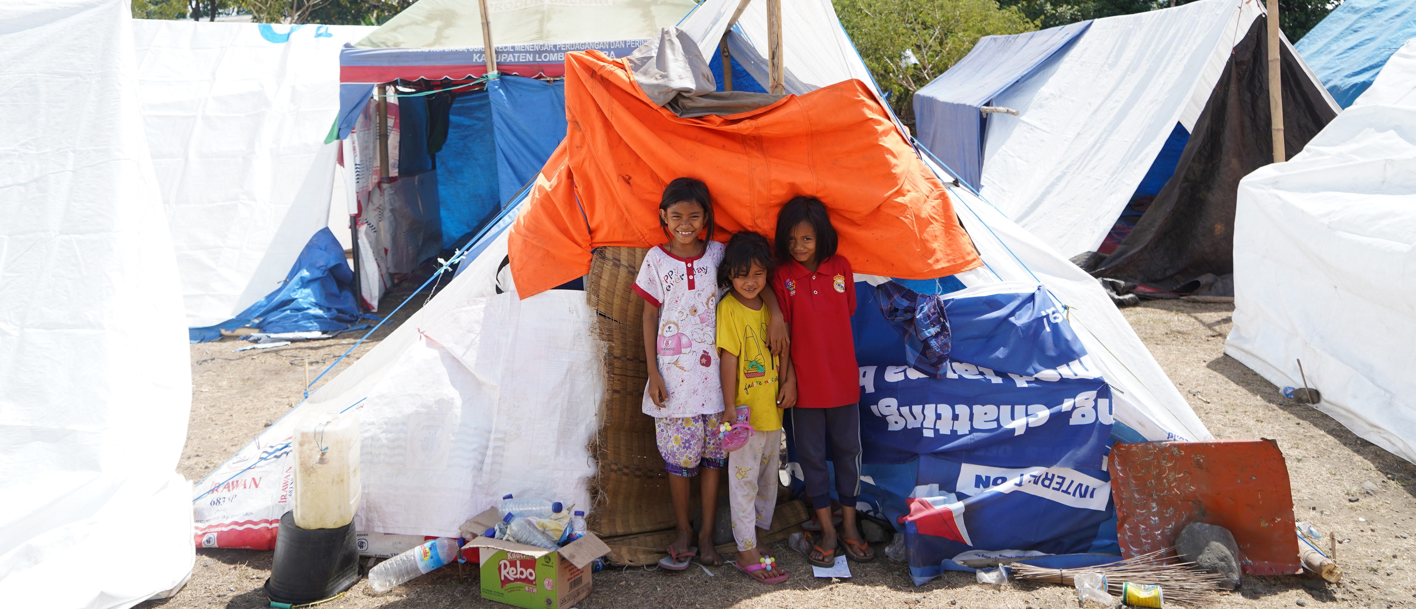 Children in front of their tent made using one of Plans shelter kits