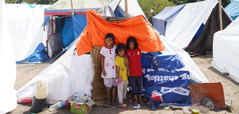 Children in front of their tent made using one of Plans shelter kits
