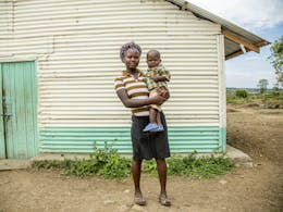tienermoeder en haar kind voor hun huis in kenia