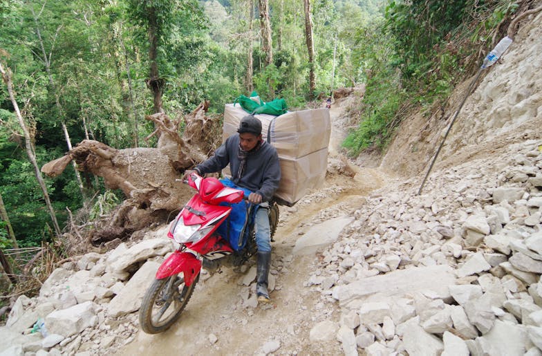 Hulp aan slachtoffers Sulawesi in volle gang | Plan International Nederland Man met scooter op slechte weg distributie naar Lindu
