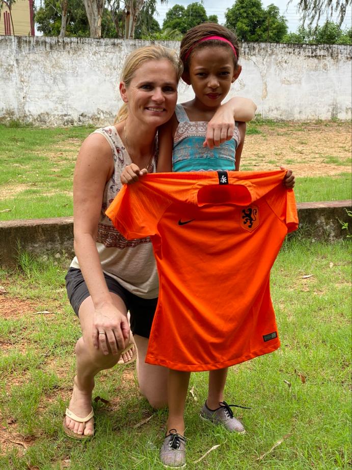 Sarina poseert met een oranje voetbalshirt en een van de kinderen.