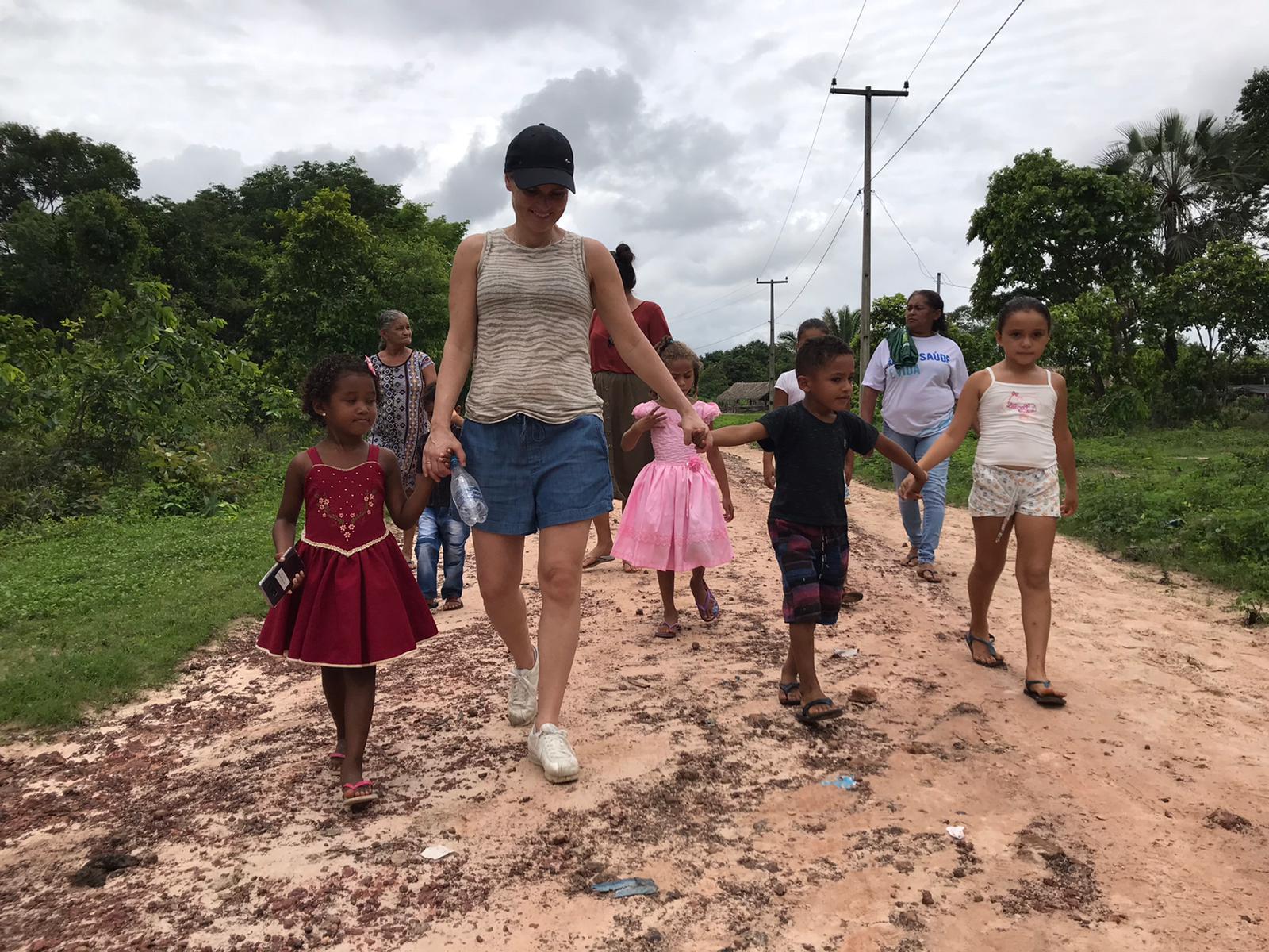 Sarina loopt met een paar kinderen over een zandweg.