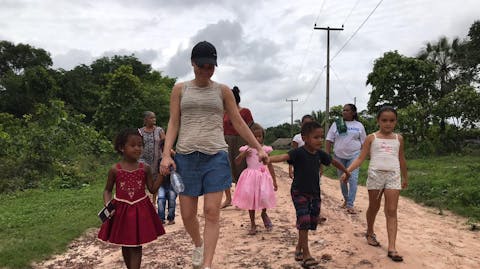 Sarina loopt met een paar kinderen over een zandweg.