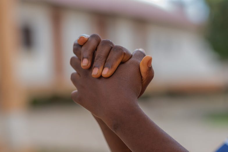 Doreen Uganda handen die elkaar vastpakken
