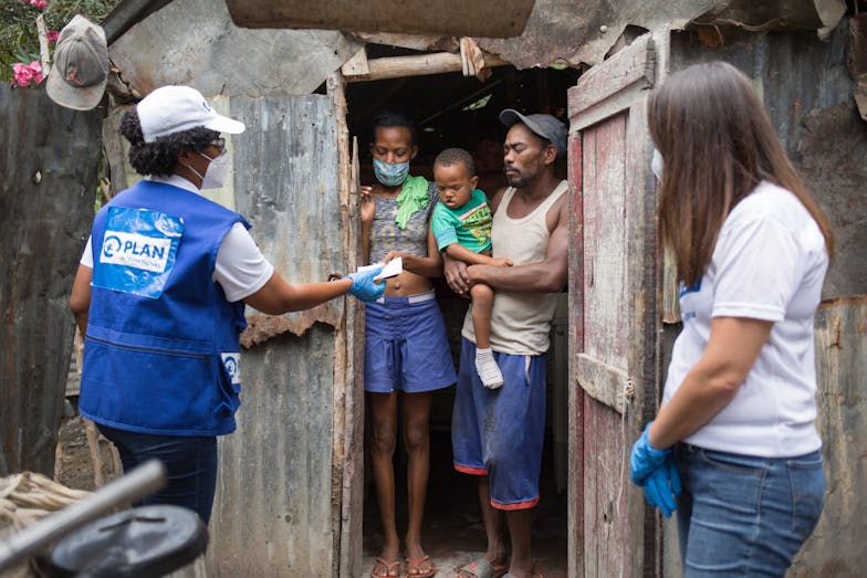 collega met Plan International jasje overhandigt pakket aan familie