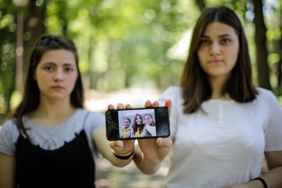 Yana (19) en Alina (21) laten een foto zien van zichzelf met hun jongere zusje