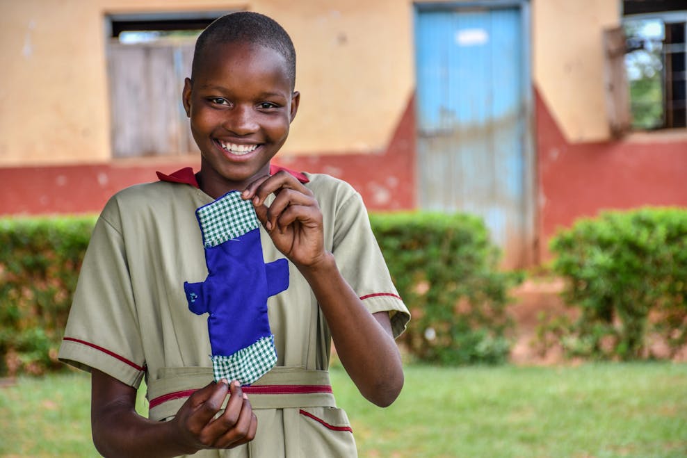 Meisje in Uganda laat herbruikbaar maandverband zien.