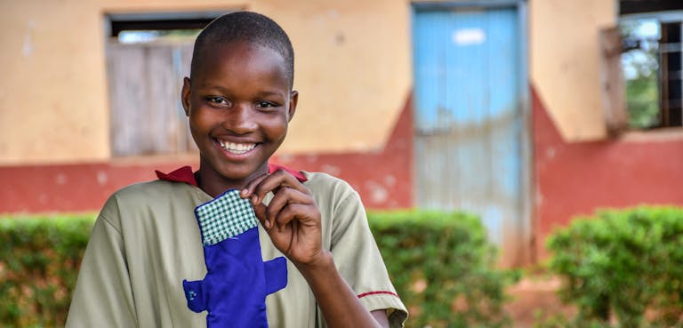 Meisje in Uganda laat herbruikbaar maandverband zien.