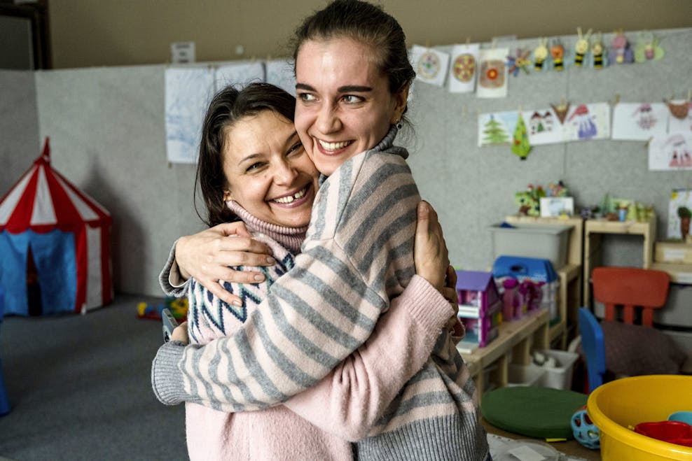 Twee vrouwen omhelzen elkaar. Ze lachen.