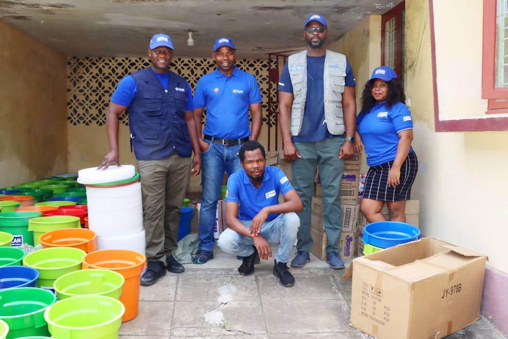 Een groep van vijf mensen met blauwe Plan International shirts staat klaar om hygiënekits uit te delen.