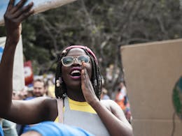 Een zwart meisje met bril komt bij een protest op voor haar rechten.