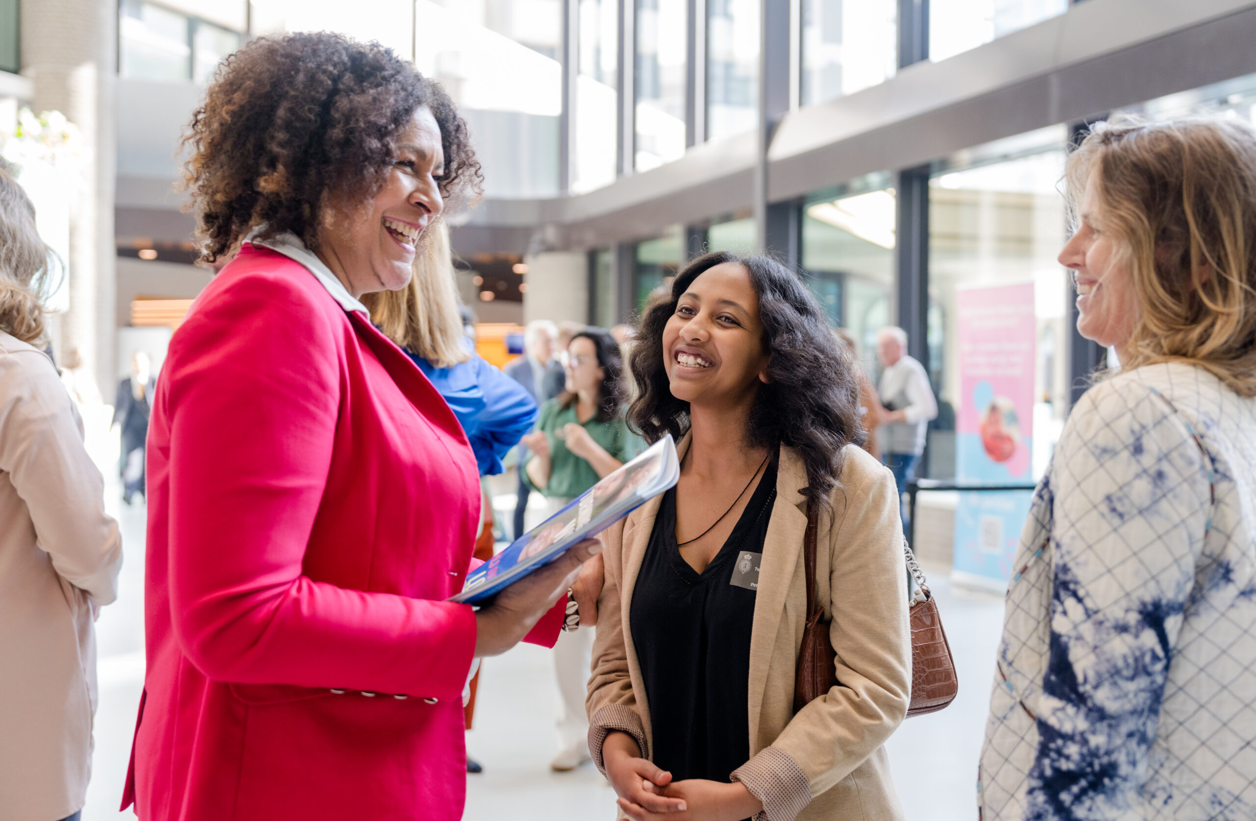 Jorien Wuite in roze pak, neemt het rapport in ontvangst. Naast haar staat Natanim die het rapport overhandigde.