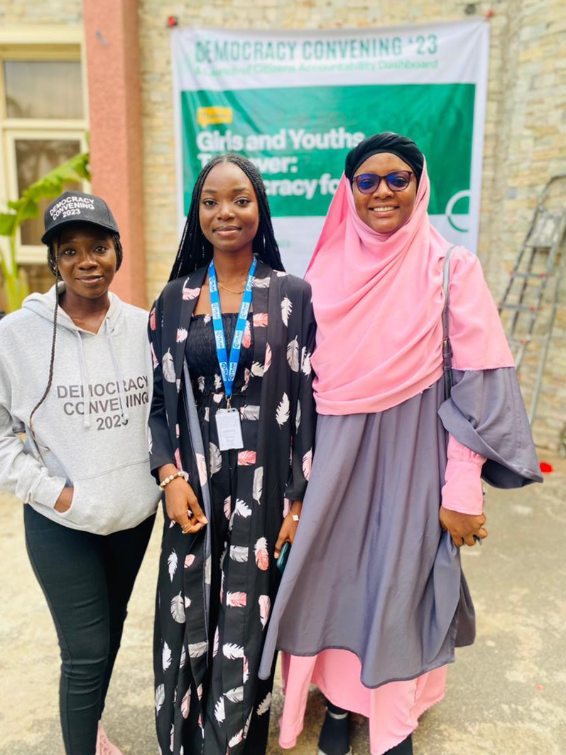 Drie vrouwen in Nigeria kijken lachend in de camera