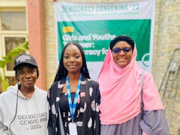 Drie vrouwen in Nigeria kijken lachend in de camera