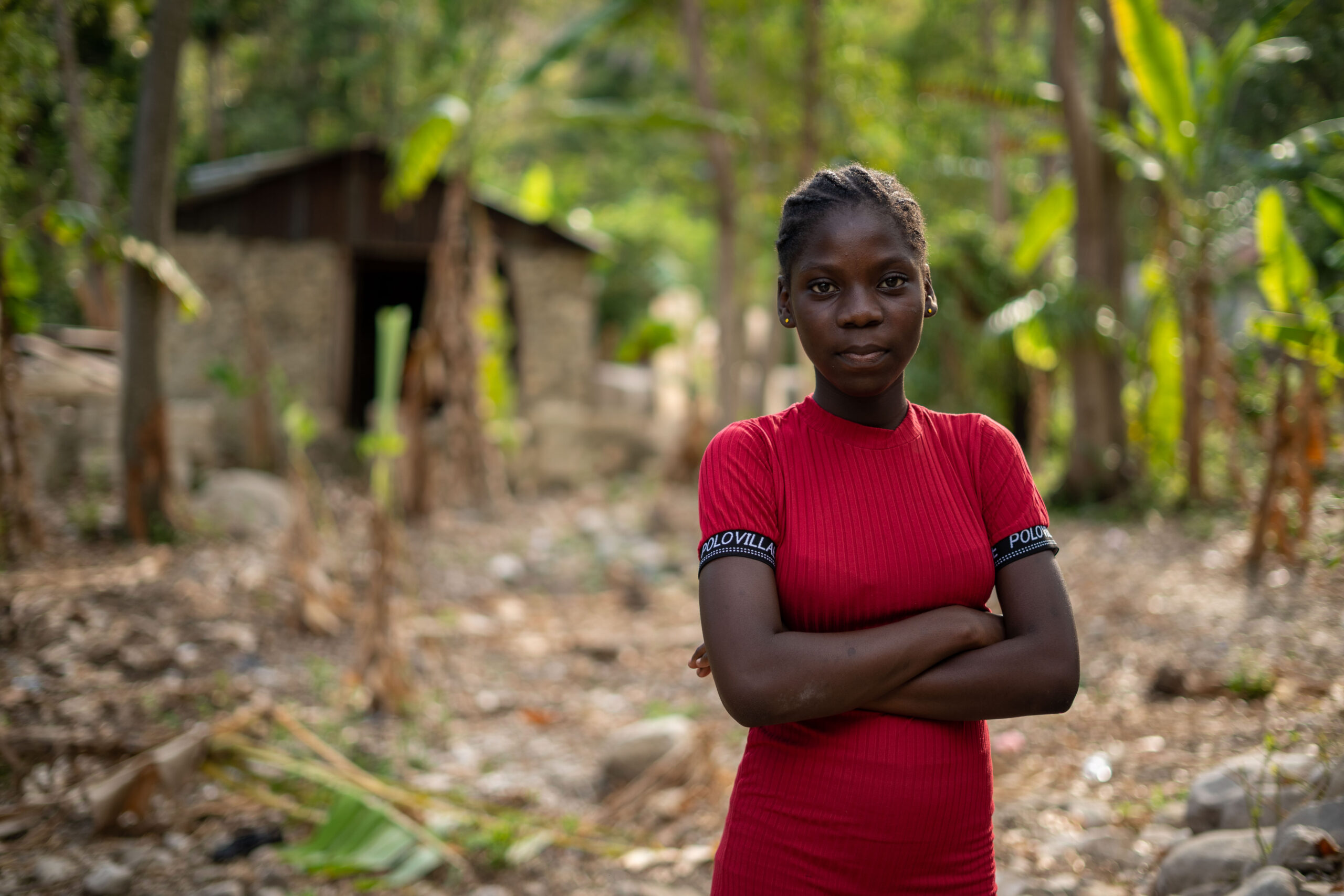 Een meisje kijkt vastberaden in de camera. Ze draagt een rood t-shirt en heeft haar armen over elkaar.