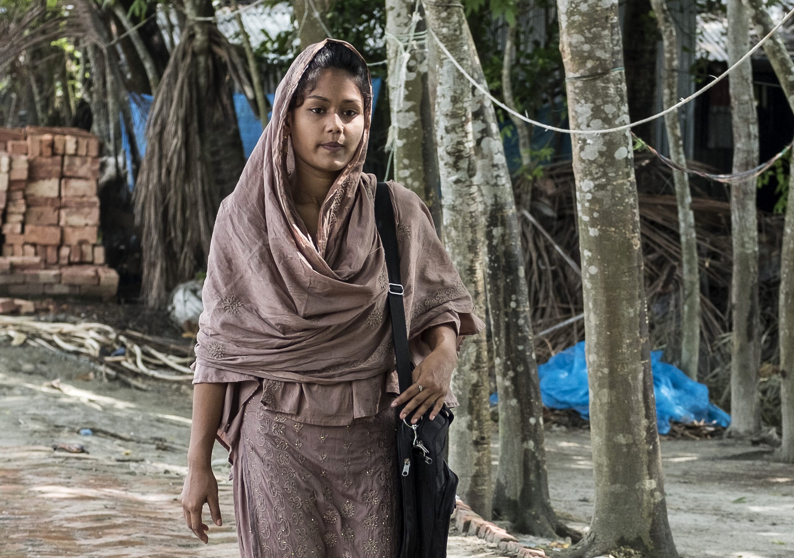 Een meisje uit Bangladesh loopt over straat. Ze draagt een roze jurk en een roze hoofddoek.