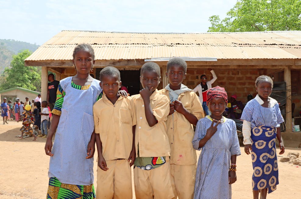 Kinderen bij het oude schoolgebouw, dat veel te klein en zwaar verouderd is. ©Plan International
