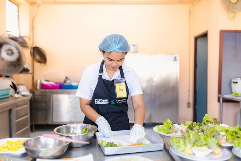 Leerling rolt springrolls in een les.