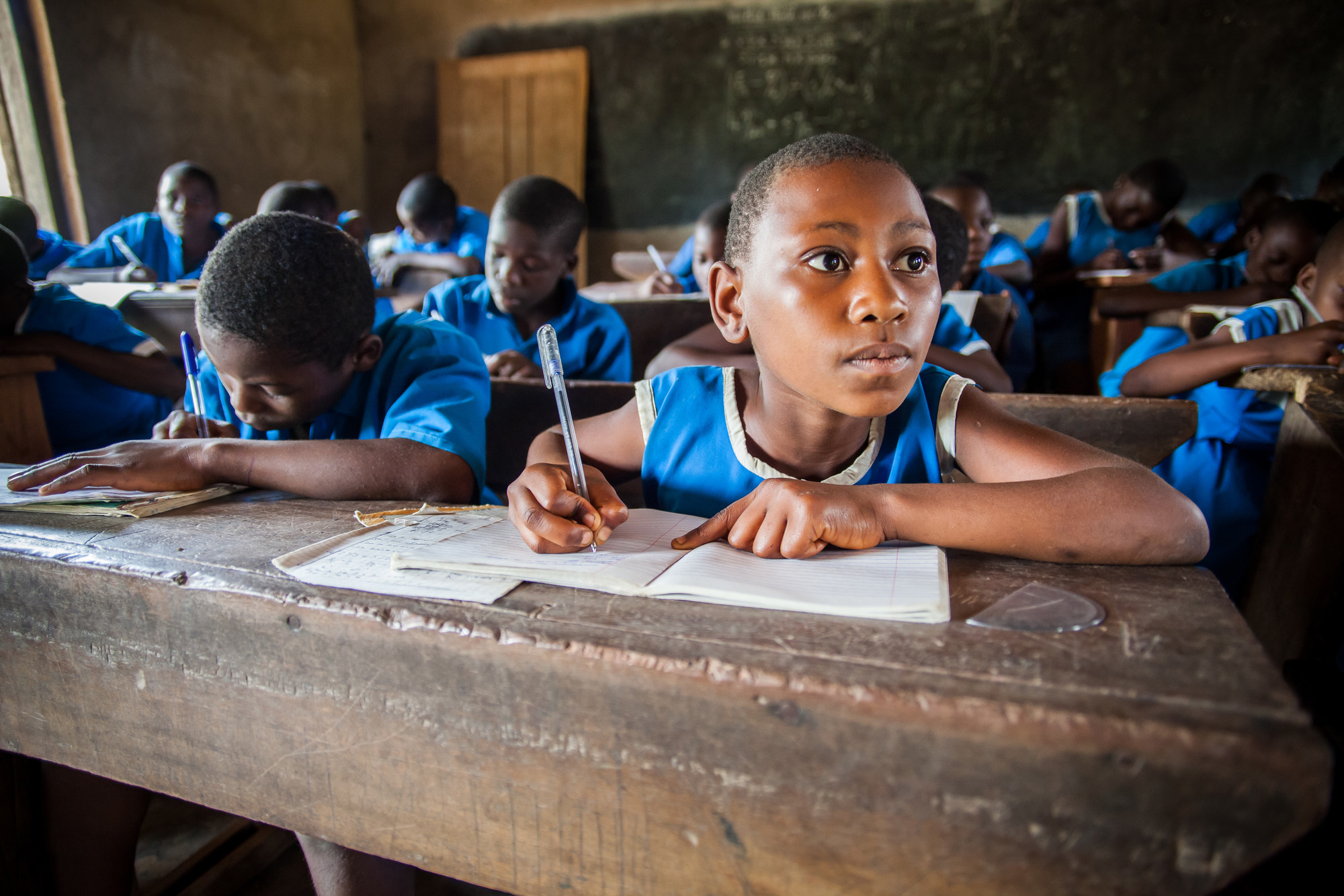 schoolmeisje schrijft in schoolbank